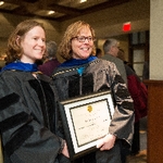 Two members of faculty pose for a picture with an award